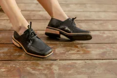 Zapato acordonado de cuero vacuno color marrón oscuro, con suela de goma, horma cuadrada y tacón bajo.