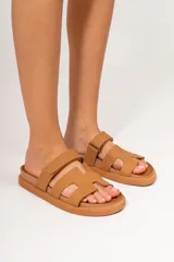 Sandalias bajas color marrón con tiras anchas y hebilla lateral.
