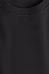 Remera negra de algodón, corte amplio, con cuello redondo y mangas cortas.