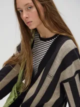 Cardigan a rayas horizontales en tonos beige y negro, de corte holgado y abierto, con botones metálicos y logo MUTMA bordado en el frente.