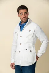 Cazadora blanca de lino con cuello camisero, cierre con botones, cuatro bolsillos frontales con solapa y corte entallado.