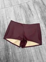 Short color cereza de tiro bajo, confeccionado en tela engomada.