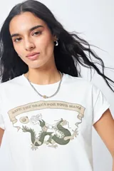 Remera color beige de manga corta con cuello redondo y estampado con ilustración gráfica al frente y frase retro.