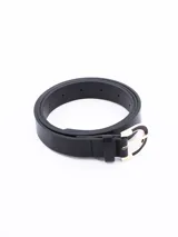 Cinto negro de cuero con hebilla metálica dorada con forma de media luna.