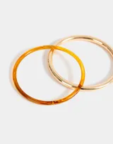 Set de dos pulseras rígidas, una de resina color carey y otra de metal dorado.
