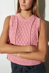 Chaleco de punto color rosa con cuello redondo y diseño trenzado.