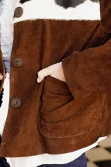 Chaqueta marrón de cuero vacuno con canesú delantero y trasero en cuero vacuno raza Holando (blanco con manchas negras), con cuello clásico, cierre frontal con botones y bolsillos laterales.