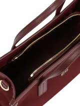 Cartera tipo tote bag de color borgoña, con acabado liso y detalles en cuero sintético del mismo tono. Presenta dos asas superiores y una correa ajustable extraíble. Incluye un colgante decorativo con el escudo de Hilfiger bordado y un dije metálico con el monograma TH.