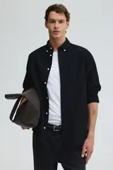 Camisa negra de algodón Oxford con cuello americano, tapeta clásica, bolsillo superior abierto y canesú en la espalda. Mangas largas con puños abotonados y bajo levemente redondeado. Corte estándar para una silueta clásica y cómoda.