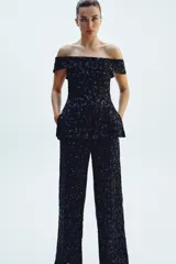 Top chaleco negro con escote recto y hombros descubiertos, con lentejuelas a tono y aberturas laterales.