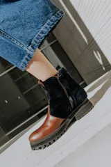 Botas de cuero marrón con paneles de corderito en color beige en la caña. Cuentan con una suela de goma tipo track en tono tostado y cierre de cremallera lateral.