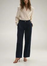 Pantalón de jean azul oscuro de corte wide leg, tiro medio, con pinzas delanteras y bolsillos laterales.