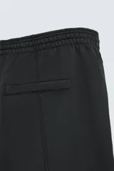 Pantalón wide fit confeccionado en tejido de algodón con interior en rizo, color negro. Cintura elástica ajustable con cordón interior, bolsillos frontales y detalle de bolsillo trasero de vivo. Perneras con costura frontal y efecto lavado.