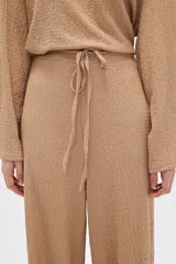 Pantalón de calce ancho y tiro alto, color beige con textura.