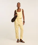 Pantalón zanahoria de cintura alta color amarillo pastel, confeccionado en viscolino con 15% de lino, con trabillas en la cintura, solapas con botón abajo de la cintura, pliegues y cierre tradicional.