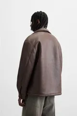 Sobrecamisa marrón de efecto piel con interior de borreguillo combinado a tono, de corte relaxed fit, cuello solapa, manga larga con puños abotonados, bolsillos de plastrón en pecho y laterales en cadera, efecto lavado y cierre frontal con botones a presión.