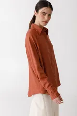 Camisa blanca de lino con botones de madera, corte recto y mangas largas.