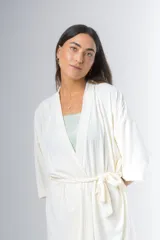 Bata tipo kimono de algodón color blanco hueso, con textura acanalada vertical. Presenta un cruce frontal asegurado con un lazo a la cintura y mangas anchas de largo al codo.
