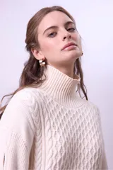 Sweater de punto color borgoña con cuello alto y diseño trenzado.