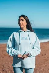 Hoodie celeste con capucha, puños y ruedo acanalados. Presenta un bordado en el pecho con motivos playeros y la frase "Glassy Waves".