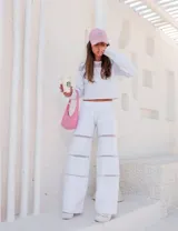 Conjunto deportivo blanco compuesto por un buzo crop con mangas largas y detalle de tul en los hombros, y un pantalón de tiro alto con cintura elástica y detalle de tul en los laterales.