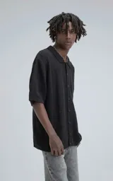 Camisa negra de manga corta tejida de punto abierto con calce oversize.