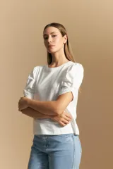 Remera blanca de cuello redondo con mangas cortas abullonadas y detalle de nudo en los puños.