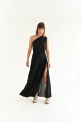 Vestido largo negro de lurex con un solo hombro y falda plisada con abertura lateral.