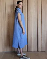 Túnica celeste de corte recto, con cuello camisero, mangas cortas, tajos laterales y cierre frontal con botones.