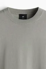 Remera verde claro de punto fino suave con remate acanalado en cuello, mangas y bajo. Corte ajustado que realza el contorno del cuerpo creando una silueta entallada.