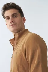 Campera marrón de algodón con cierre frontal, cuello alto, bolsillos laterales, puños y logo bordado en el pecho.