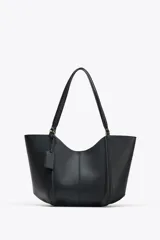 Bolso de hombro tipo shopper color beige, con doble asa y cierre imantado. Incluye una cartera interior con cierre de cremallera.