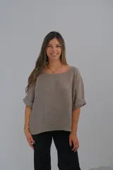 Blusa de lino color visón, de corte holgado, con cuello redondo y mangas cortas con dobladillo.