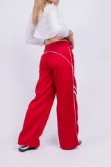 Pantalón deportivo rojo con detalles de líneas blancas curvas en los laterales.