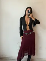 Body negro con escote en V pronunciado, mangas largas acampanadas y abertura en el abdomen.