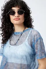 Top translúcido azul con estampado abstracto, de manga corta y tejido liviano con sutil brillo metálico.