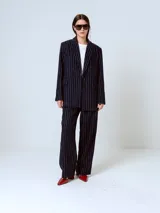 Blazer azul marino con rayas verticales blancas, de corte clásico, con solapas de muesca, cierre frontal con dos botones, bolsillos con solapa y abertura en la espalda.