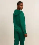Campera deportiva verde esmeralda de modal, con capucha ajustable con cordón, cierre frontal con cremallera y bolsillos laterales.