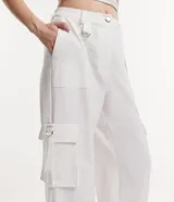 Pantalón de vestir blanco, de corte recto, con bolsillos cargo laterales y detalle de aro metálico en la trabilla.