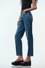 Jeans de tiro alto color celeste, corte mom fit, con cinco bolsillos y cierre frontal con cremallera y botón.
