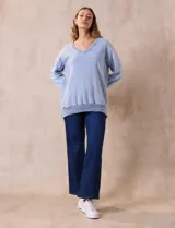 Buzo celeste de algodón con efecto lavado, escote en V, cuello, puños y ruedo acanalados y tajos laterales.