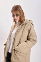 Campera color beige con capucha, cierre frontal con cremallera y diseño acolchado con costuras en forma de rombos.