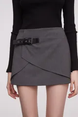 Falda mini de diseño asimétrico en color negro con detalle de hebilla en la cintura.