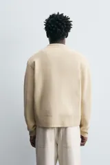 Chaqueta de punto color mostaza, corte relaxed fit, con cuello elástico, manga larga, bolsillos en la cadera, acabados en rib y cierre frontal con cremallera.