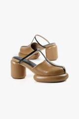 Mule color caramelo con plataforma y taco cilíndrico, tira superior negra y puntera cuadrada.