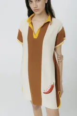 Vestido tipo polo tejido en jersey liviano de algodón y acrílico, con rayas horizontales en color crudo y marrón. Presenta bordado XL de un ají rojo y terminaciones acanaladas en las mangas.