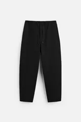 Pantalón negro de corte carrot fit, confeccionado en tejido de algodón. Cuenta con cintura elástica ajustable con cordón, bolsillos frontales y un bolsillo trasero de plastrón.