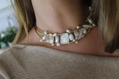 Gargantilla rígida dorada con doble aro y apliques de perlas irregulares y piezas de nácar.