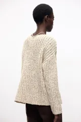 Sweater color crema de tejido de punto grueso, con cuello redondo amplio y mangas largas.