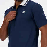 Chomba de piqué azul marino con cierre parcial con cremallera, cuello tipo polo con ribete doble blanco, mangas cortas y logo de New Balance bordado en blanco en el pecho.
